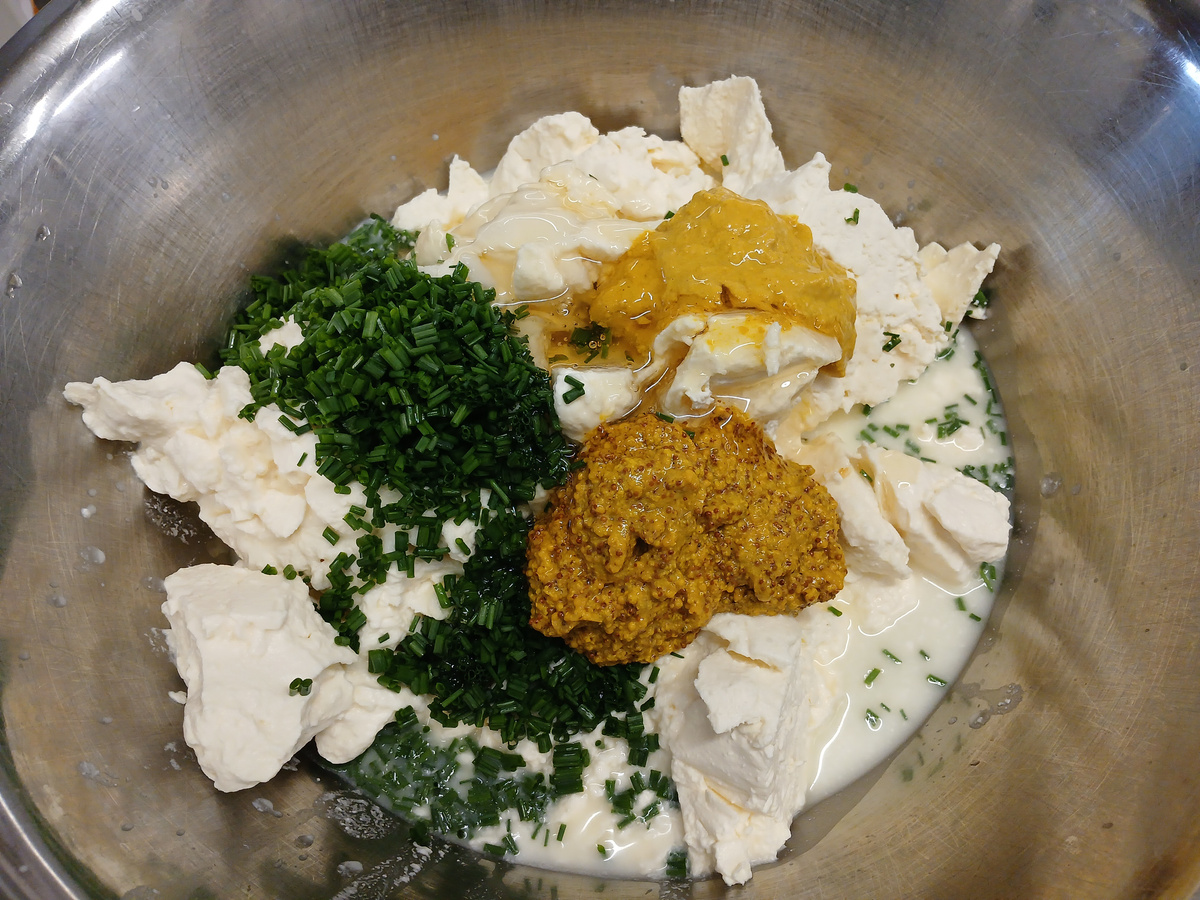 KI generiert: Zutaten in einer Schüssel: Frischkäse, Schnittlauch, Senf, Honig und Sahne.