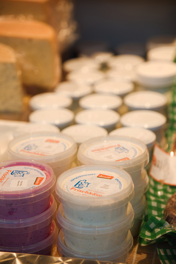 KI generiert: Verpackte Frischkäse-Produkte in verschiedenen Sorten, im Verkaufsregal präsentiert.