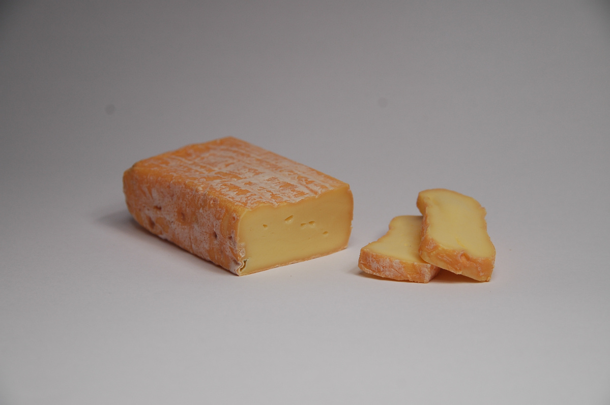 KI generiert: Ein Stück Weichkäse mit einer weichen, gelben Mitte und einigen geschnittenen Scheiben daneben.